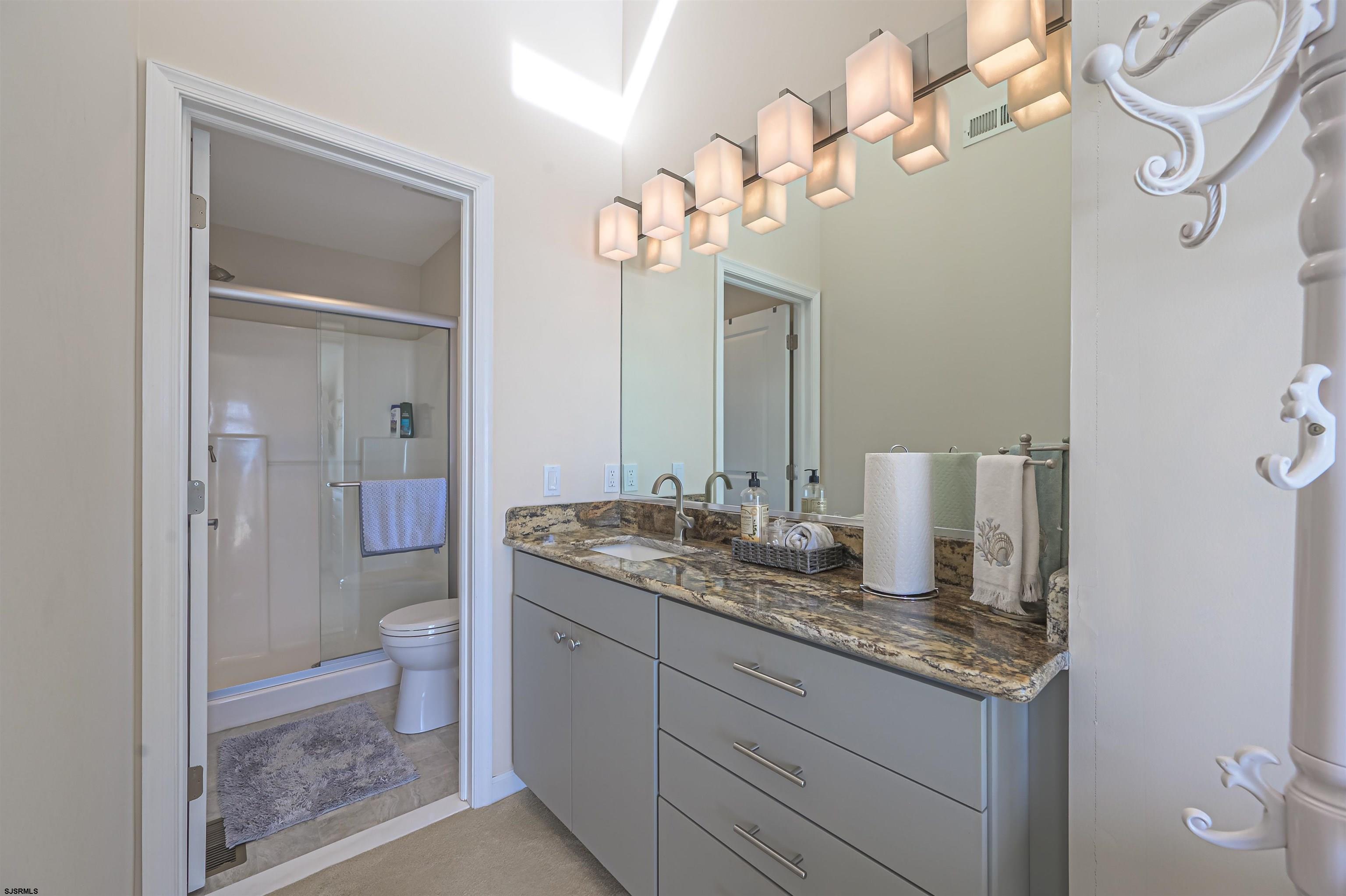 815 East Brigantine Avenue, Unit 7 Brigantine, NJ 08203 - Photo 20 of 31 a bathroom with a granite countertop sink a toilet and a mirror