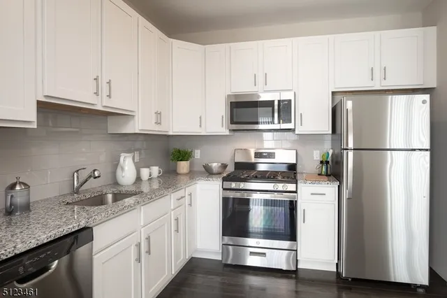a kitchen with granite countertop white cabinets and stainless steel appliances