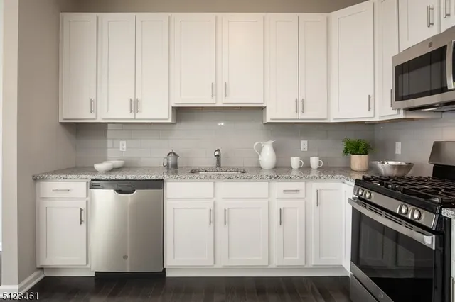 a kitchen with stainless steel appliances granite countertop white cabinets a sink and dishwasher
