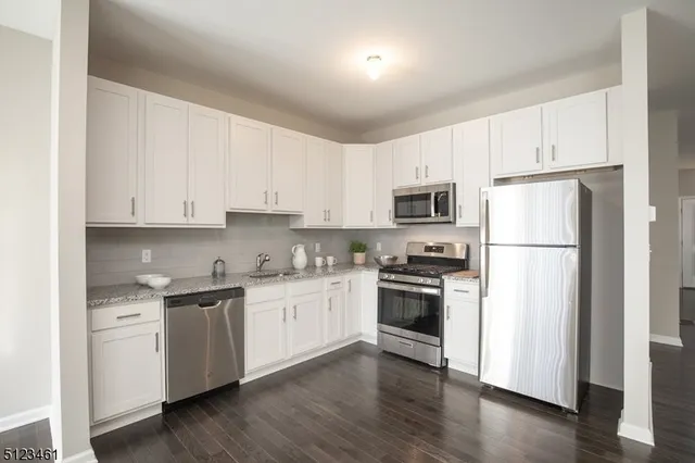 a kitchen with cabinets stainless steel appliances and wooden floor