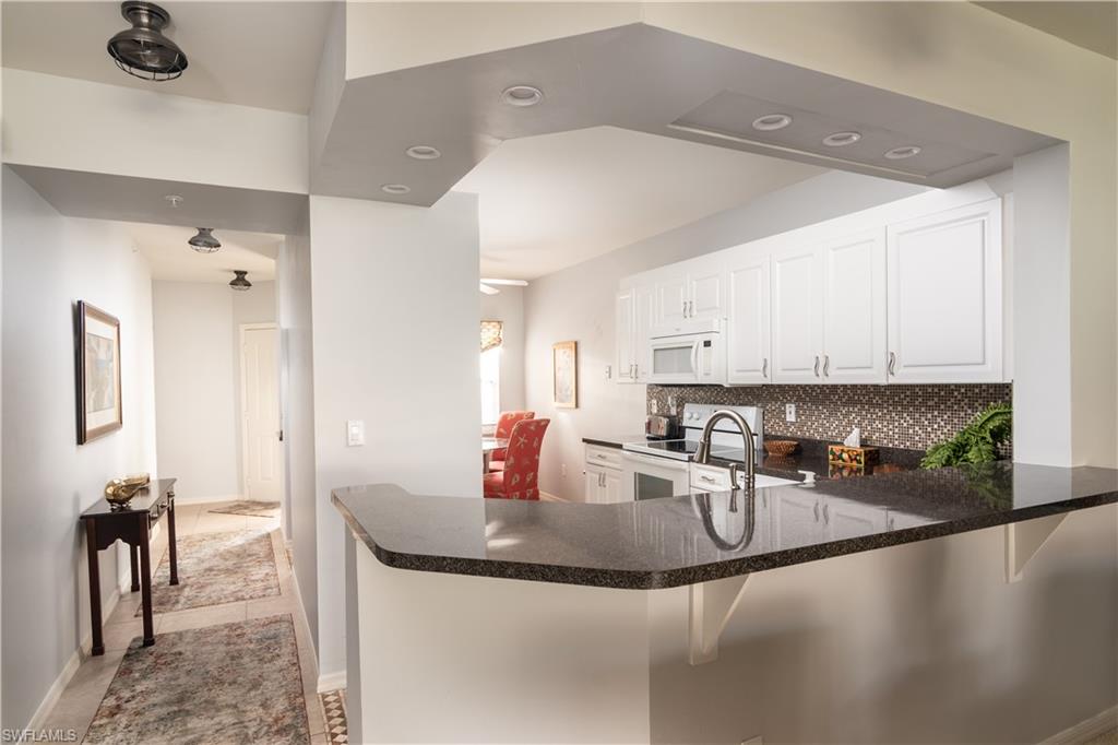 2585 Old Groves Road, Unit L102 Naples, FL 34109 - Photo 4 of 29 a kitchen with granite countertop a sink a stove and cabinets