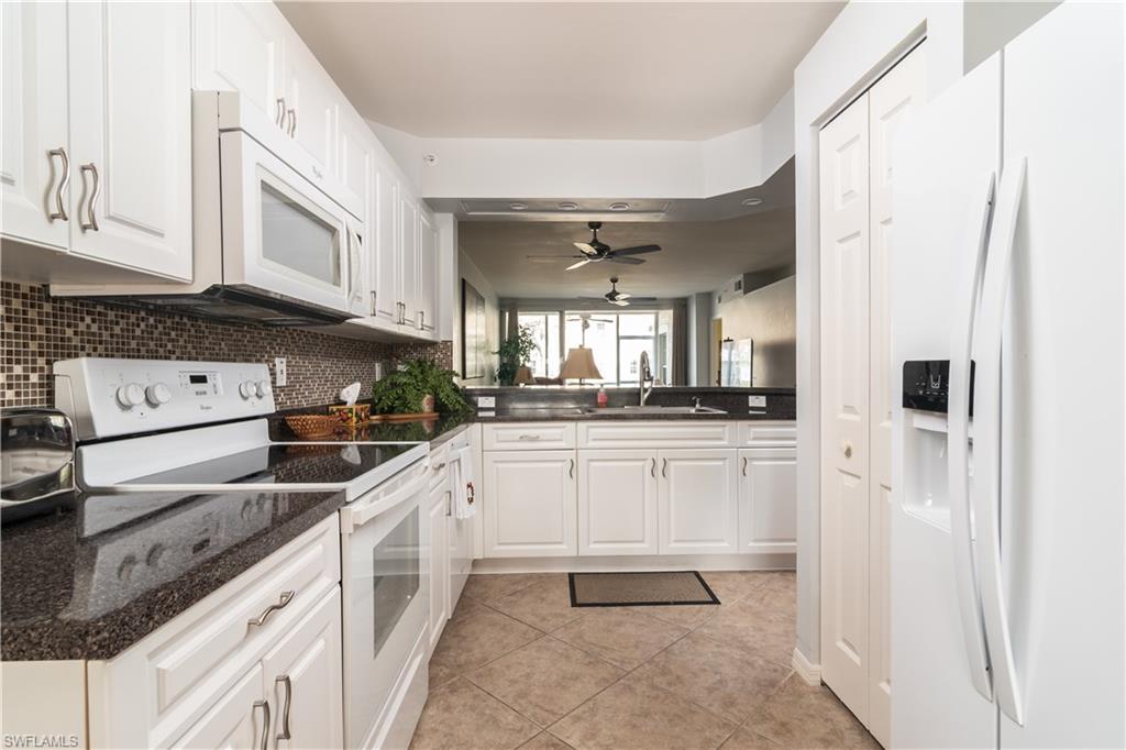 2585 Old Groves Road, Unit L102 Naples, FL 34109 - Photo 7 of 29 a kitchen with stainless steel appliances granite countertop a refrigerator and a sink