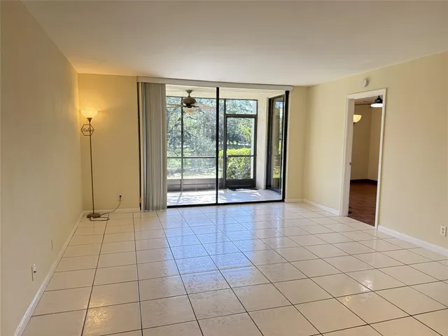 a view of an empty room with window and chandelier