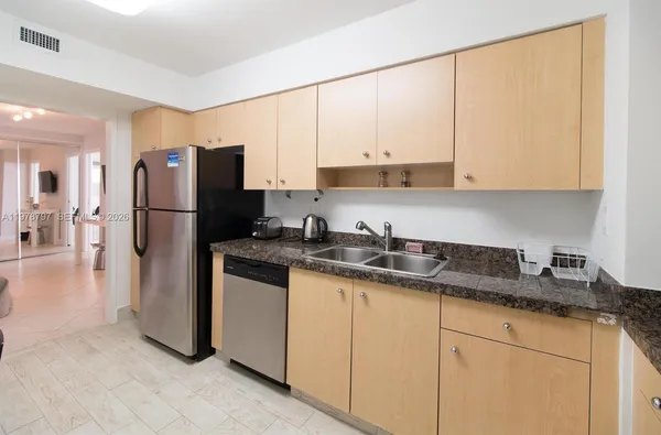 a kitchen with stainless steel appliances granite countertop a refrigerator a sink and white cabinets