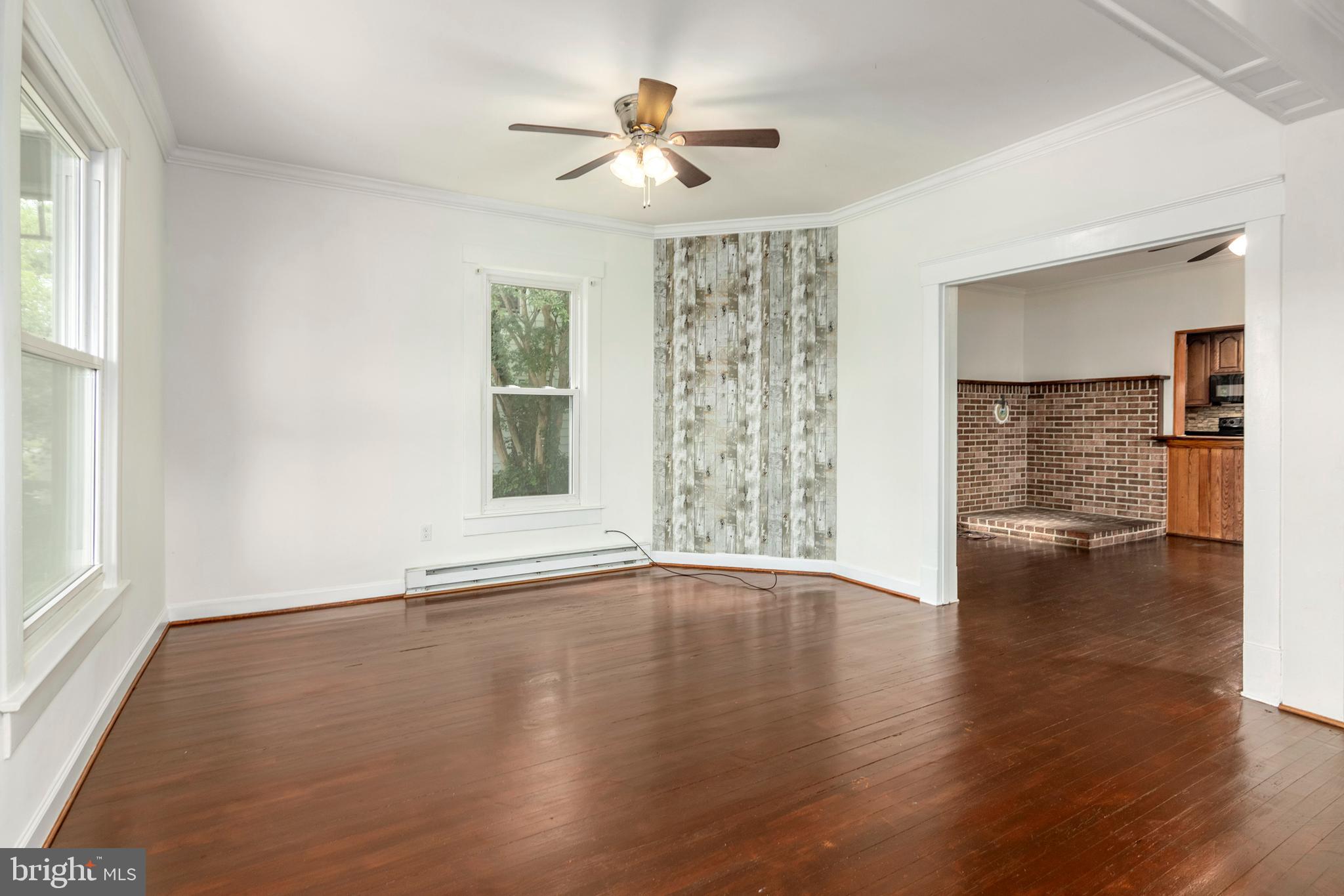 201 Washington Street Cambridge, MD 21613 - Photo 2 of 31 an empty room with wooden floor chandelier fan and windows