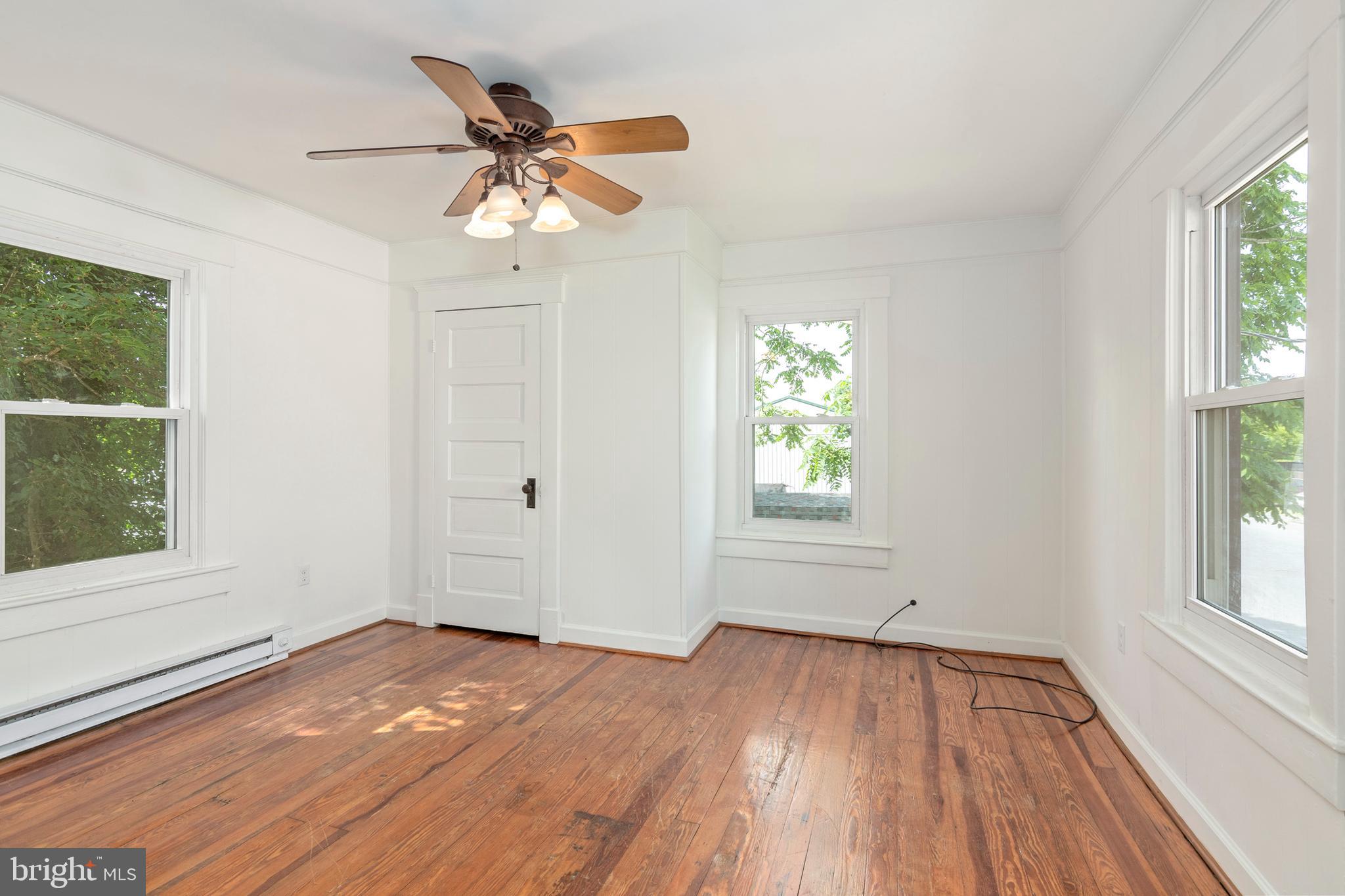 201 Washington Street Cambridge, MD 21613 - Photo 24 of 31 an empty room with wooden floor chandelier fan and windows