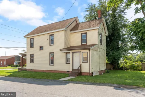 a view of a white house with a big yard and large trees