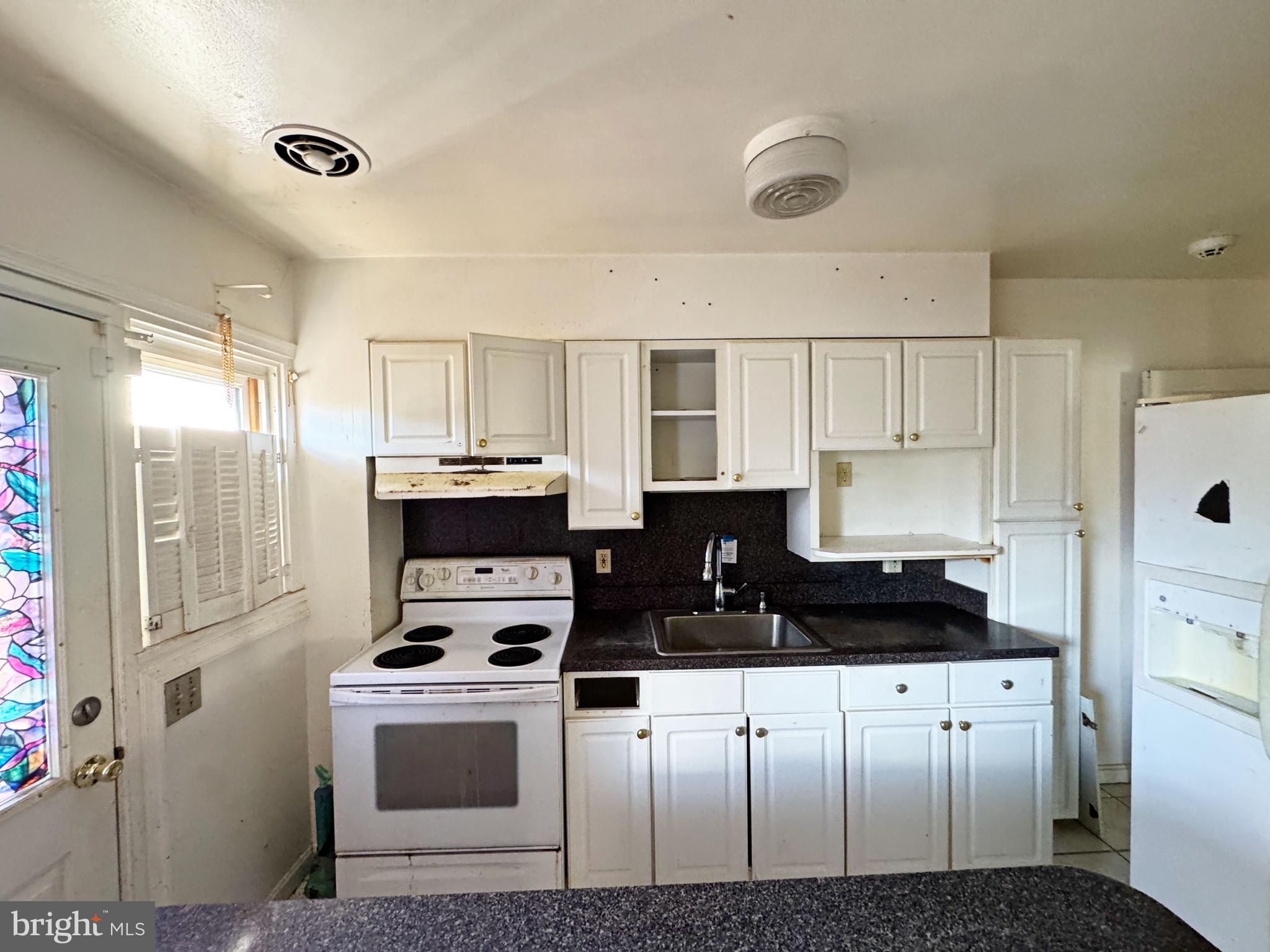 44 North Athol Avenue Baltimore, MD 21229 - Photo 9 of 18 a kitchen with granite countertop a refrigerator stove and white cabinets