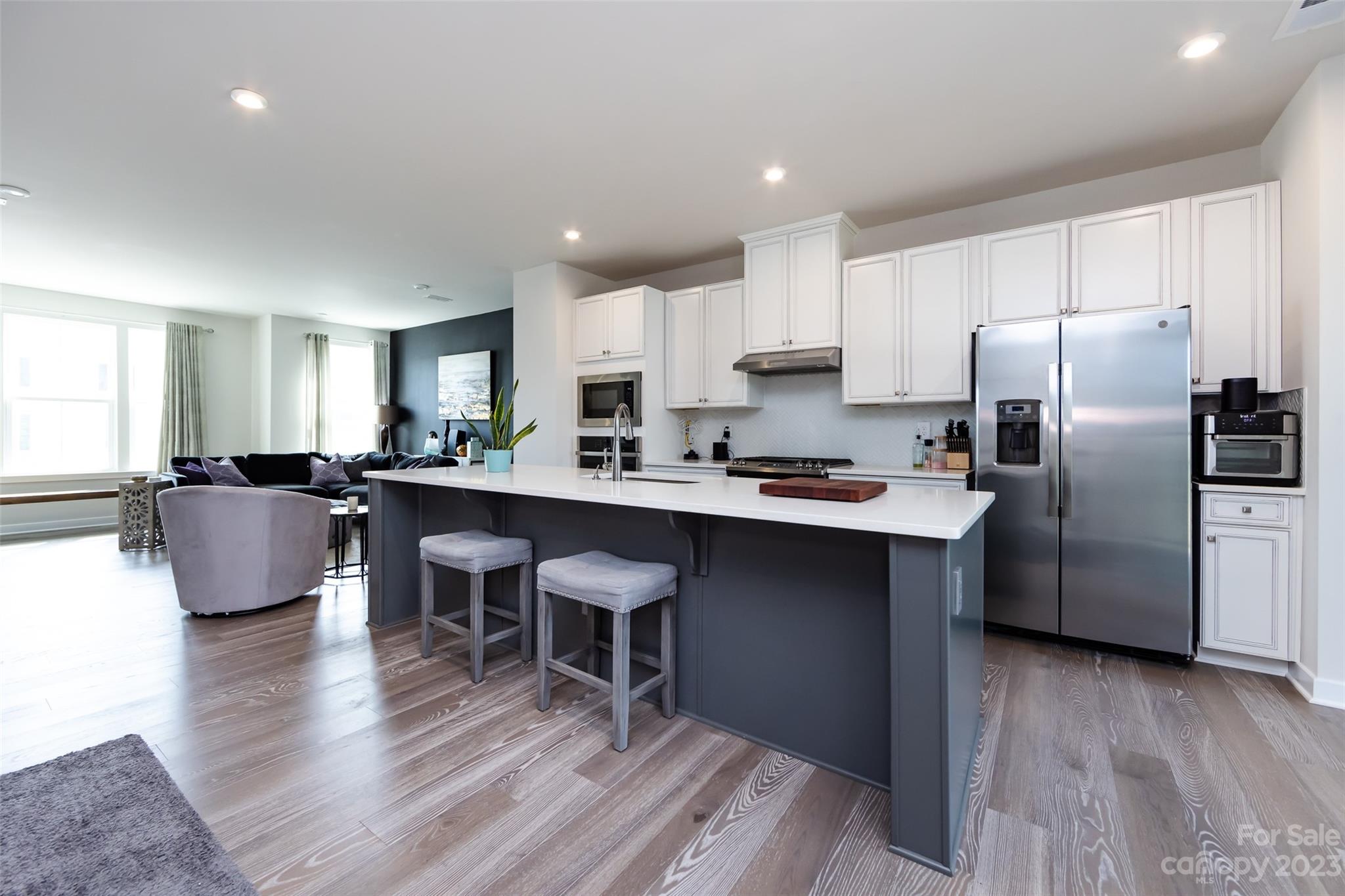 606 Crudent Road Tega Cay, SC 29708 - Photo 9 of 47 a kitchen with stainless steel appliances a refrigerator a stove a sink dishwasher and a dining table with wooden floor
