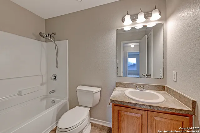 a bathroom with a granite countertop sink a toilet and shower
