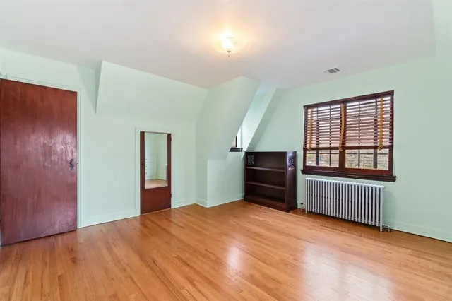 a view of an empty room with wooden floor and windows