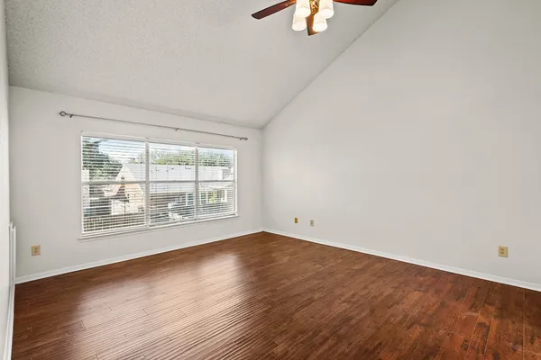an empty room with wooden floor and windows