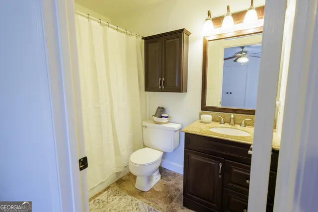 a bathroom with a granite countertop toilet and a sink