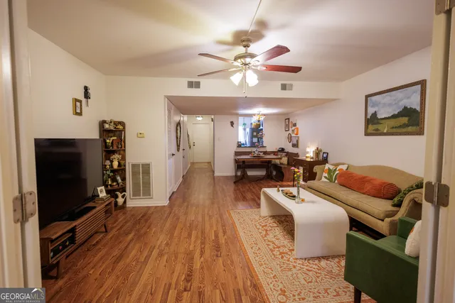 a living room with furniture a ceiling fan and a flat screen tv