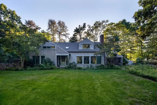 a view of a house next to a big yard and large trees