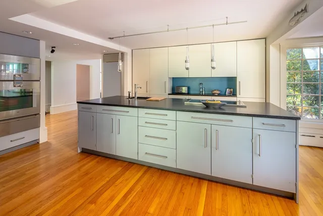 a kitchen with stainless steel appliances a sink cabinets and wooden floor