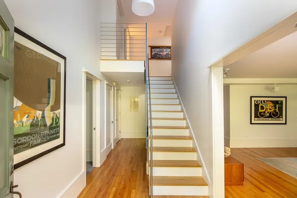 a view of a hallway with wooden floor and staircase