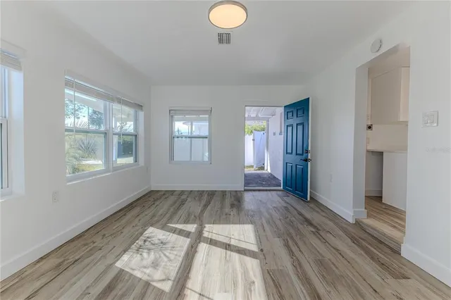 an empty room with wooden floor and windows