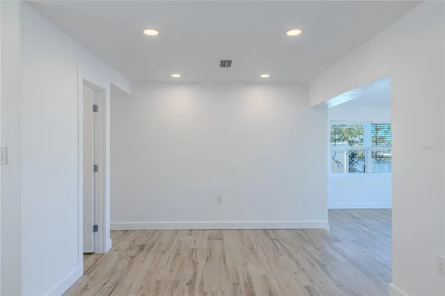 a view of an empty room with a window and wooden floor