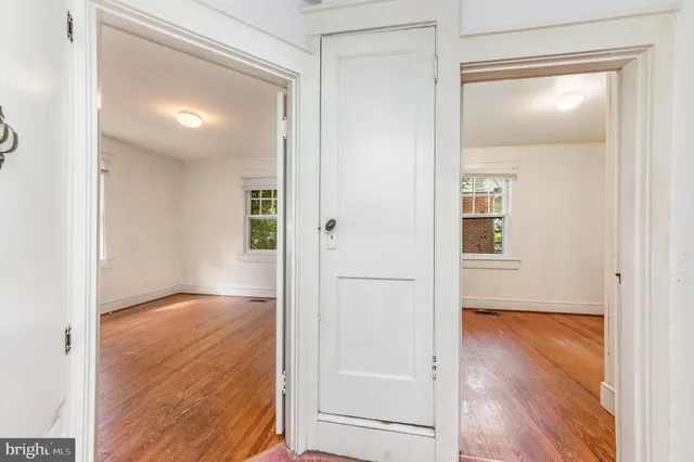 an empty room with wooden floor mirror and windows