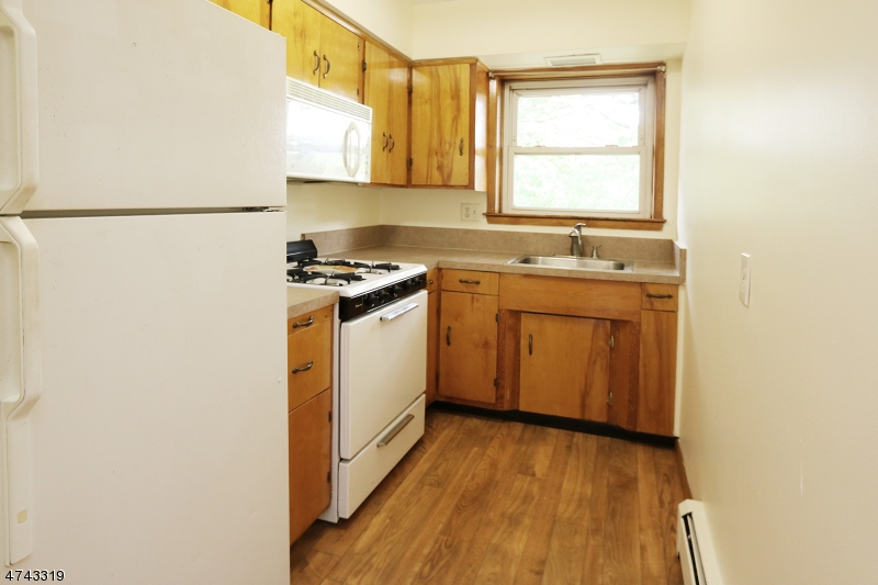 2 Westervelt Place, Unit C203 Clifton, NJ 07011 - Photo 4 of 11 a kitchen with a stove a sink and a window