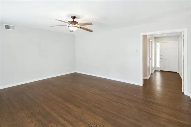 a view of a room with wooden floor ceiling fan and window