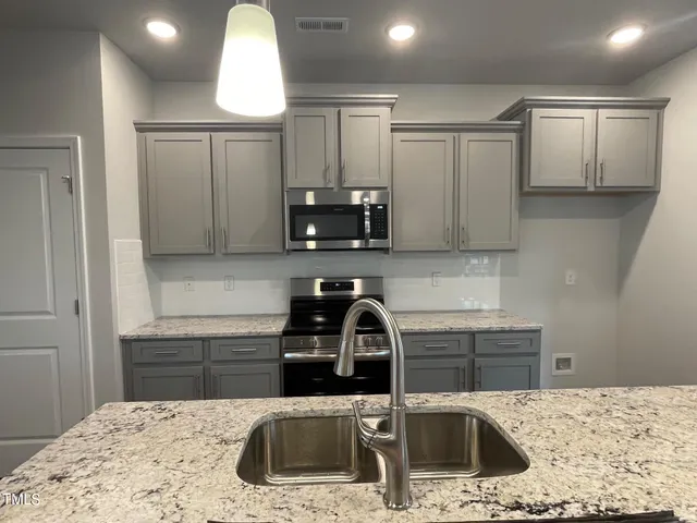 a kitchen with granite countertop a sink and a stove top oven with wooden floor