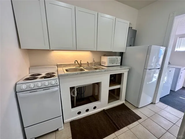 a kitchen with granite countertop white cabinets and white appliances