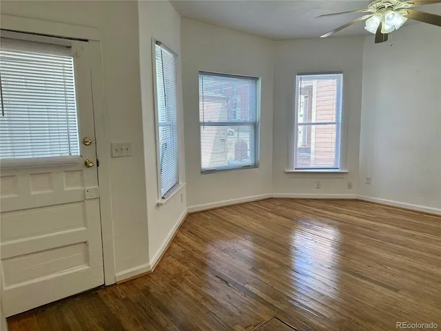 a view of an empty room with a window and wooden floor
