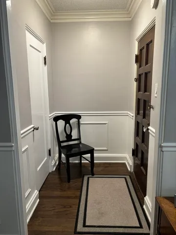 a view of a hallway to a livingroom with wooden floor and furniture