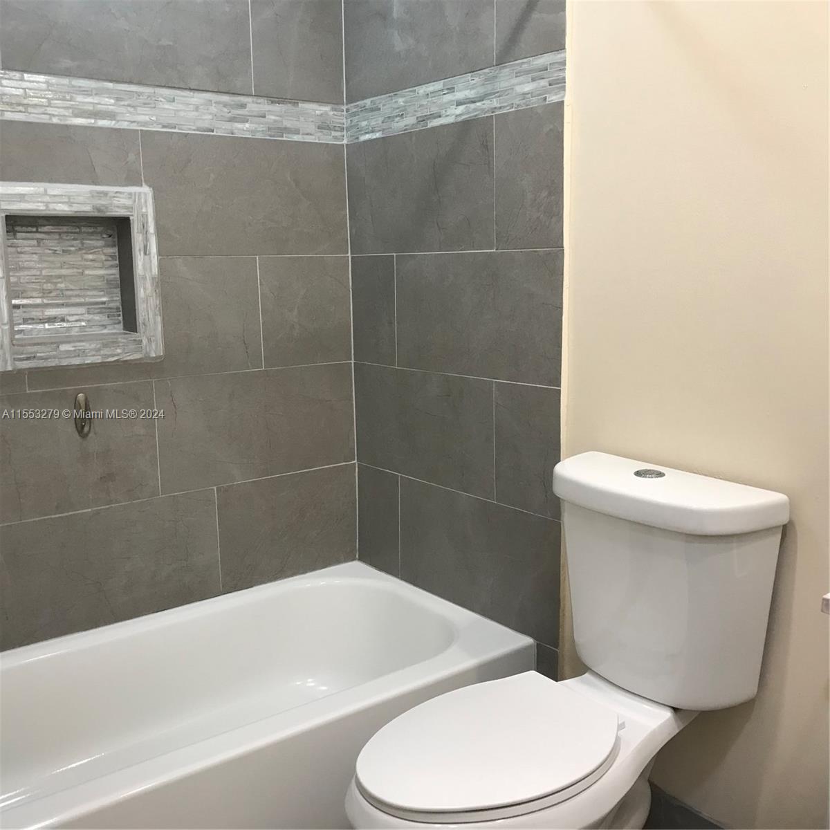 7512 Southwest 26th Court, Unit 12 Davie, FL 33314 - Photo 19 of 30 a white toilet and tub sitting next to a bathroom sink