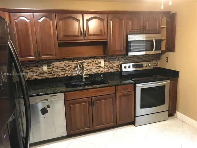 a kitchen with granite countertop a stove microwave and sink