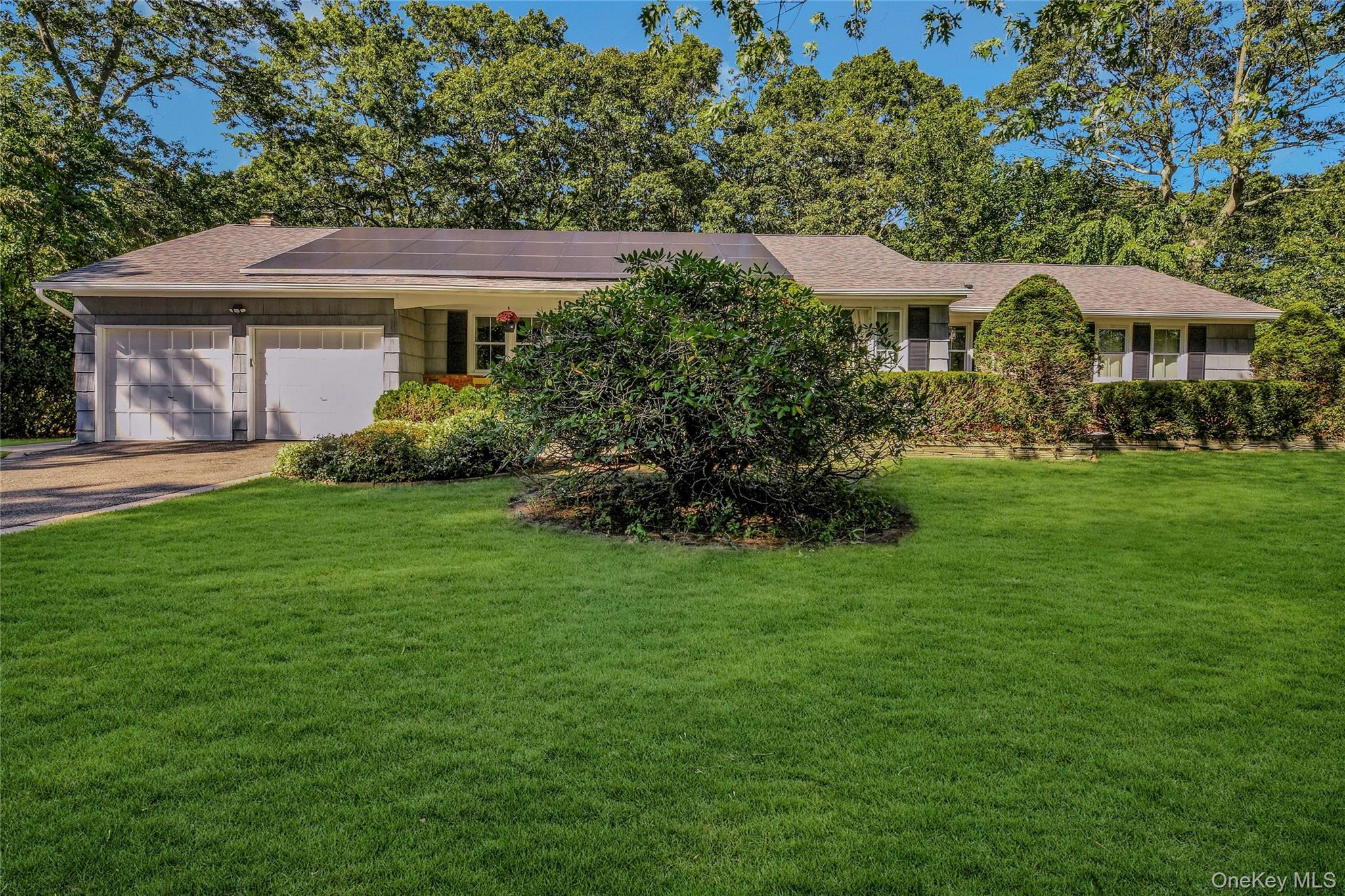 19 Fox Road East Setauket, NY 11733 - Photo 1 of 1 Ranch-style home with a front lawn, driveway, an attached garage, and roof mounted solar panels