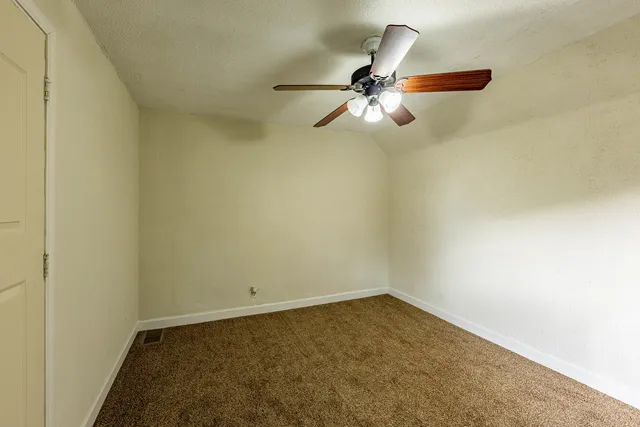 an empty room with a ceiling fan and window
