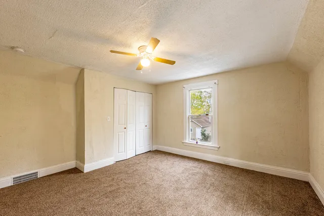 an empty room with windows and fan