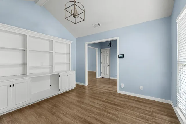 a view of an empty room with closet and wooden floor
