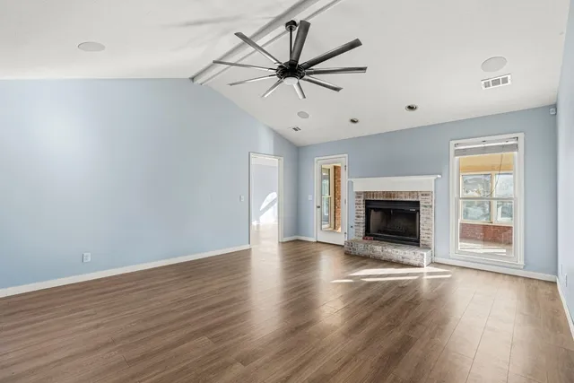 a view of a livingroom with a fireplace a ceiling fan and wooden floor