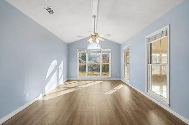 a view of an empty room with a window and wooden floor