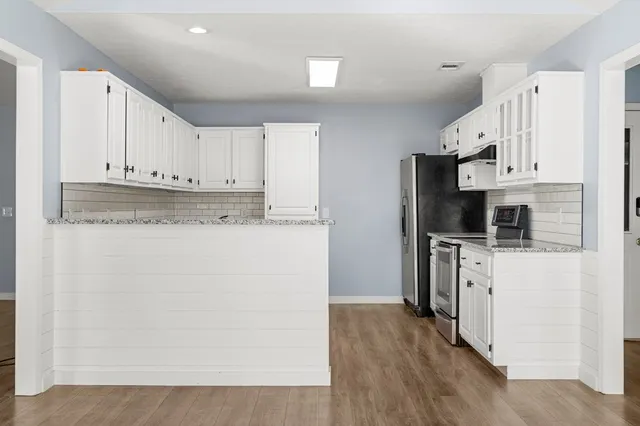 a kitchen with stainless steel appliances white cabinets and a refrigerator