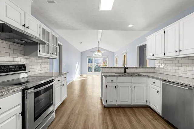 a kitchen with granite countertop a sink cabinets stainless steel appliances and a counter space