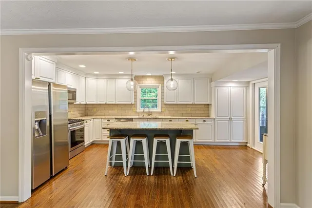 a kitchen with stainless steel appliances granite countertop a kitchen island hardwood floor and a sink