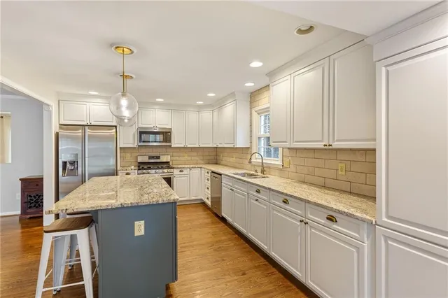 a large kitchen with kitchen island granite countertop a stove top oven a sink a counter space and cabinets