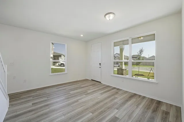 a view of an empty room with a window and wooden floor
