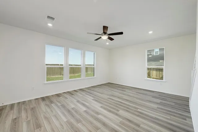 a view of an empty room with a window and a ceiling fan