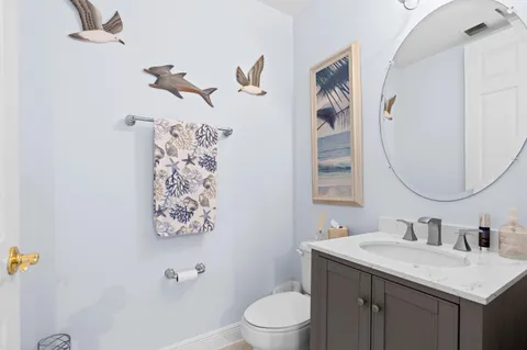 a bathroom with a granite countertop sink mirror vanity and toilet