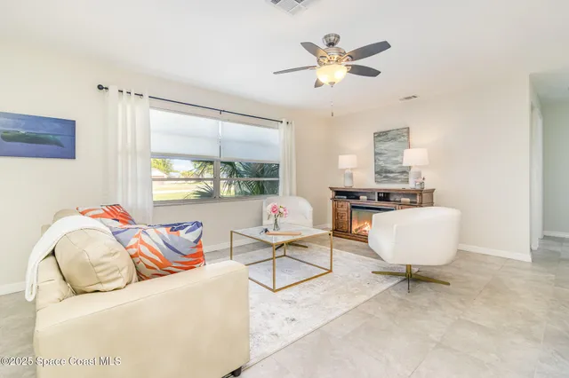 a living room with furniture a ceiling fan a window and a flat screen tv