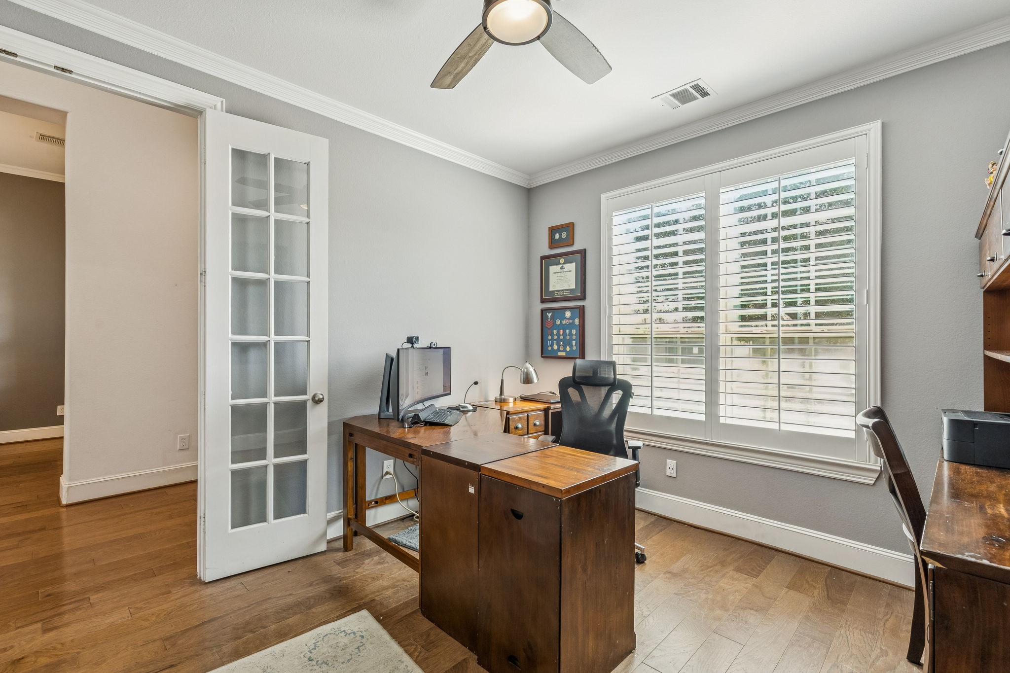 29918 Valley Terrace Drive Fulshear, TX 77406 - Photo 11 of 27 Located off the main entry, this dedicated home office features elegant French doors and shutters. The space is finished with crown molding and warm laminate wood flooring, providing a quiet and professional environment for remote work.