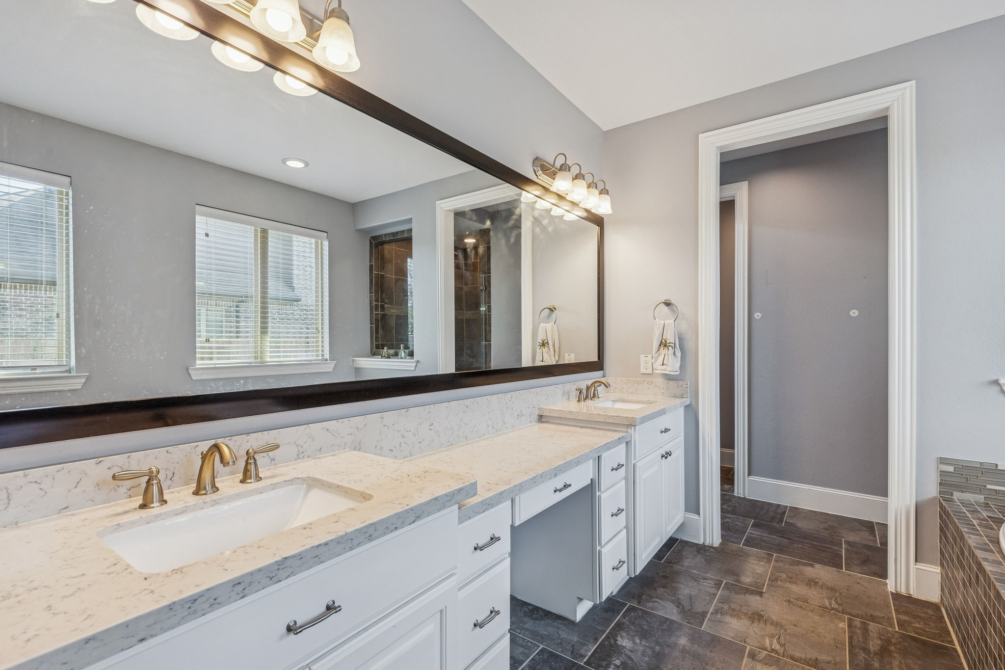 29918 Valley Terrace Drive Fulshear, TX 77406 - Photo 13 of 27 The spacious primary bath features a long dual-sink vanity with elegant stone countertops, abundant cabinetry, and a full-width mirror that enhances the light-filled space. Designed for everyday comfort, it offers plenty of room for two while maintaining a clean, modern feel.