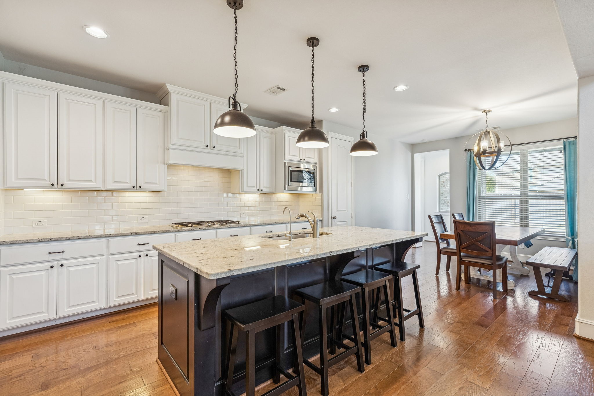 29918 Valley Terrace Drive Fulshear, TX 77406 - Photo 8 of 27 This chef-inspired kitchen is a masterpiece of function and style, featuring a large granite island, designer pendant lighting, and under-cabinet illumination. High-end finishes include soft-closing drawers and cabinets paired with a classic subway tile backsplash.