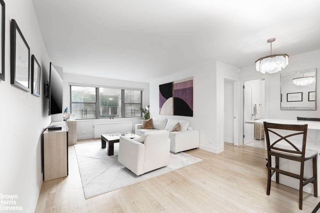 10 West 15th Street, Unit 1014 Manhattan, NY 10011 - Photo 3 of 19 a living room with furniture a flat screen tv and a large window